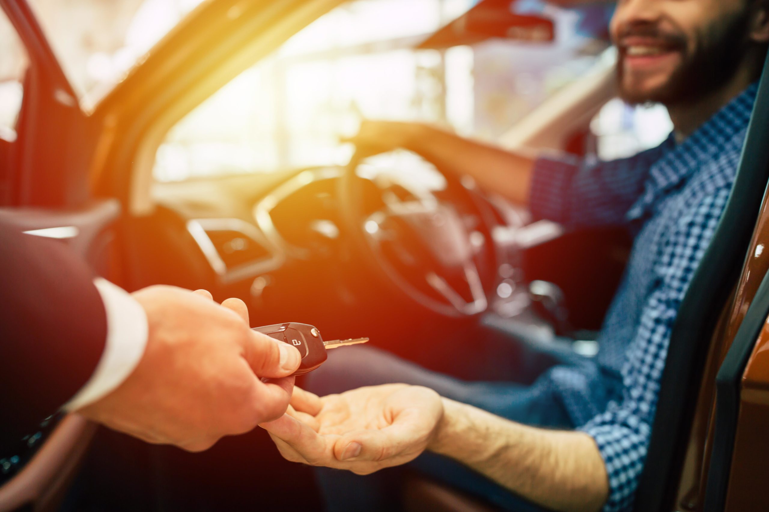 Someone handing over the keys and ownership to a new vehicle owner