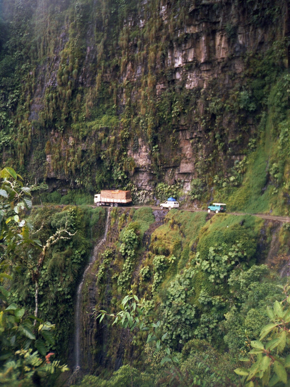 Roadway with 2 cars and a truck along a treacherous roadway