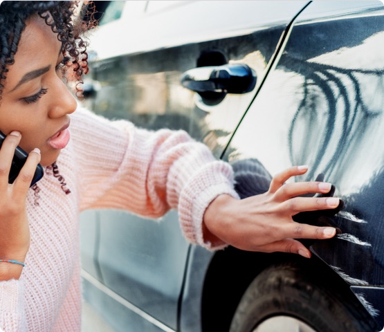 Person inspects large scratches on outside of car after being in accident